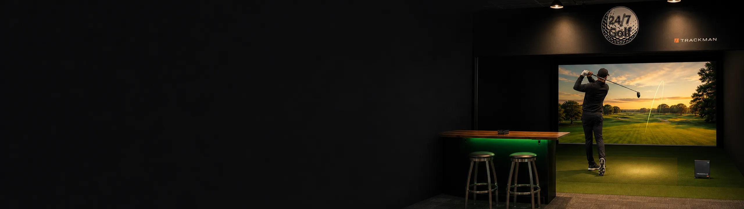 TrackMan simulator bay glowing in a dark room